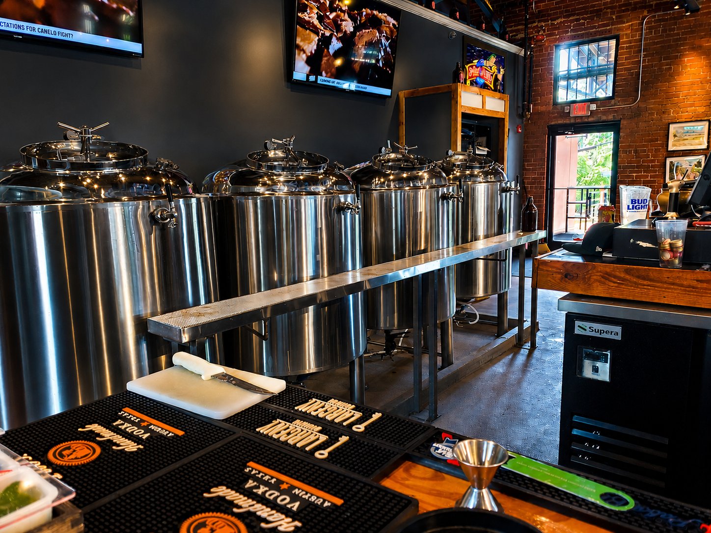 Four-tank EZBrew install integrated into a sports bar with brick walls and TVs above